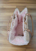 a luxury leather dog carrier seen from above. It has a fluffy fur liner.